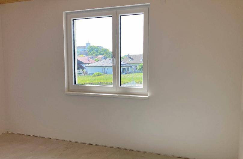 Leerer Raum mit Fenster und Blick auf die umliegende Bebauung und Landschaft.