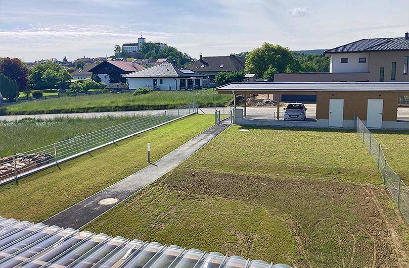 Weitläufiger Blick über die grüne Landschaft mit einem Schloss in der Ferne und Carport.