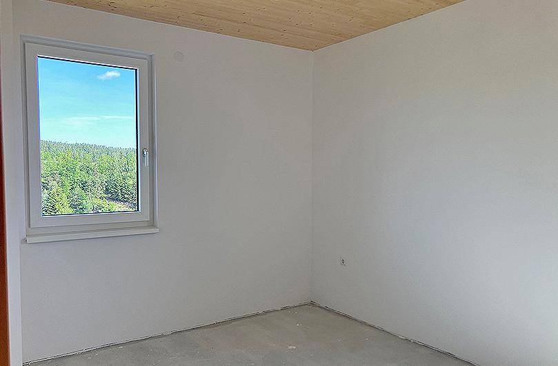 Heller Raum mit Fenster und weitem Blick auf die bewaldete Landschaft.