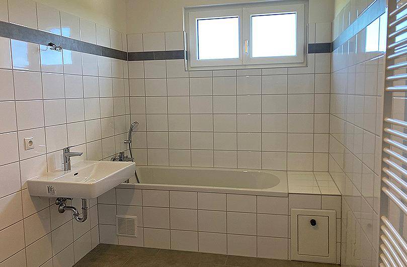 Helles Badezimmer mit Badewanne, Waschbecken und beheiztem Handtuchhalter.