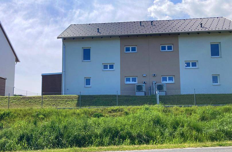 Rückseite des Doppelhauses mit Wärmepumpen und Blick auf die grüne Umgebung.