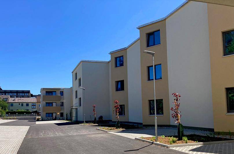 Neubauwohnungen mit moderner Architektur und gepflegter Außenanlage an einem sonnigen Tag.