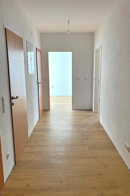 Heller Flur mit hellem Holzfußboden und mehreren Türen, der zu weiteren Räumen führt.