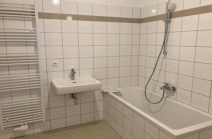 Modern gefliestes Badezimmer mit Badewanne, Waschbecken und beheiztem Handtuchhalter.