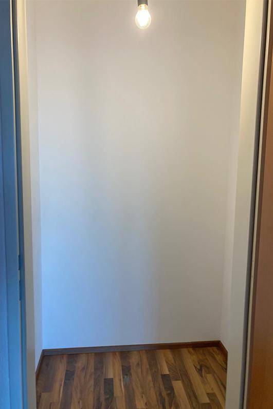 Kleiner, leerer Raum mit Laminatboden und weiß gestrichenen Wänden, ideal als Abstellraum.