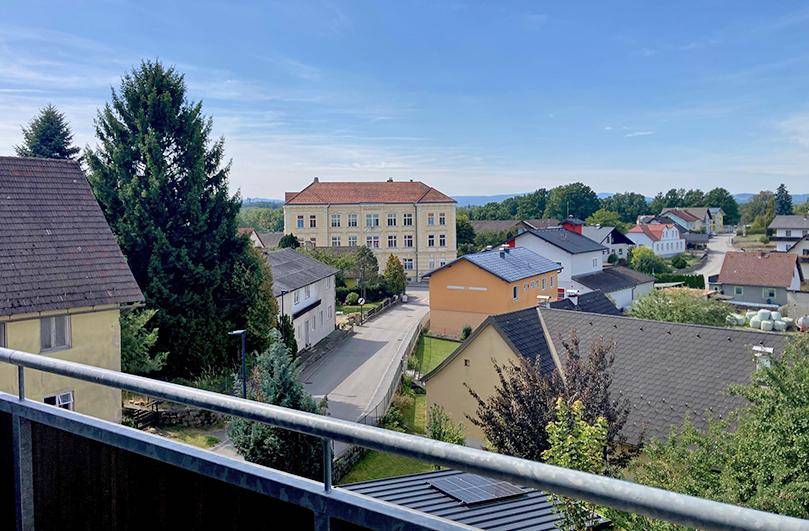 Weitläufiger Blick vom Balkon über eine ländliche Siedlung mit viel Grün und Häusern.