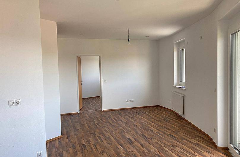 Geräumiger, heller Wohnbereich mit Laminatboden und großen Fenstern, bereit zum Einzug.