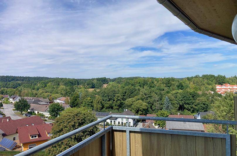 Panoramablick vom Balkon auf eine grüne Hügellandschaft und die umliegende Natur.