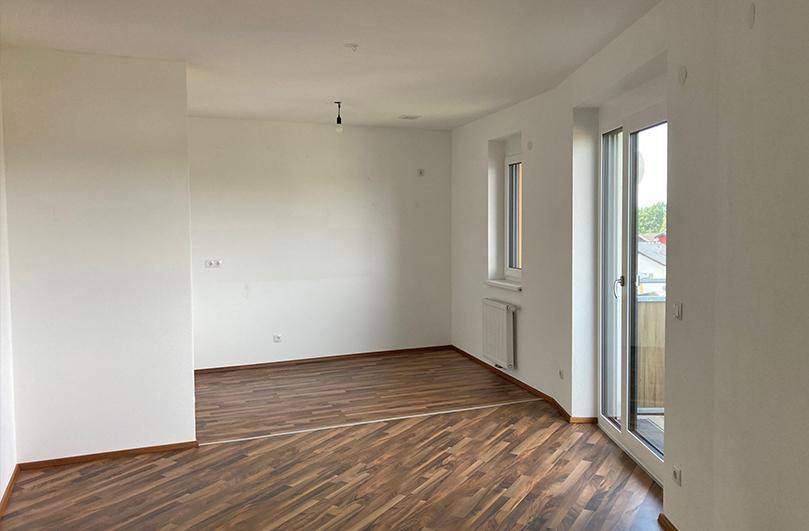 Geräumiger Wohnbereich mit Laminatboden, großen Fenstern und viel Tageslicht, bereit zum Einrichten.