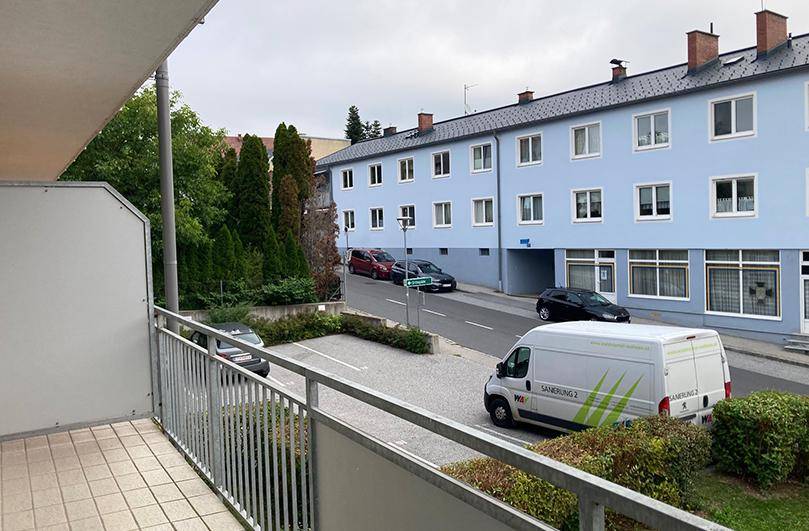 Balkon mit Fliesenboden und Blick auf die Straße und umliegende Gebäude.