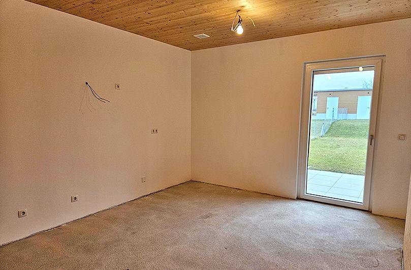 Heller Raum im Rohbau mit Holzdecke und direktem Zugang zum Garten.