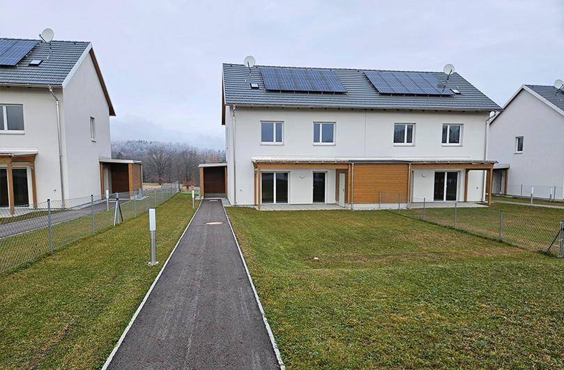 Reihe von Doppelhäusern mit Gärten, Carports und Photovoltaikanlagen auf den Dächern.