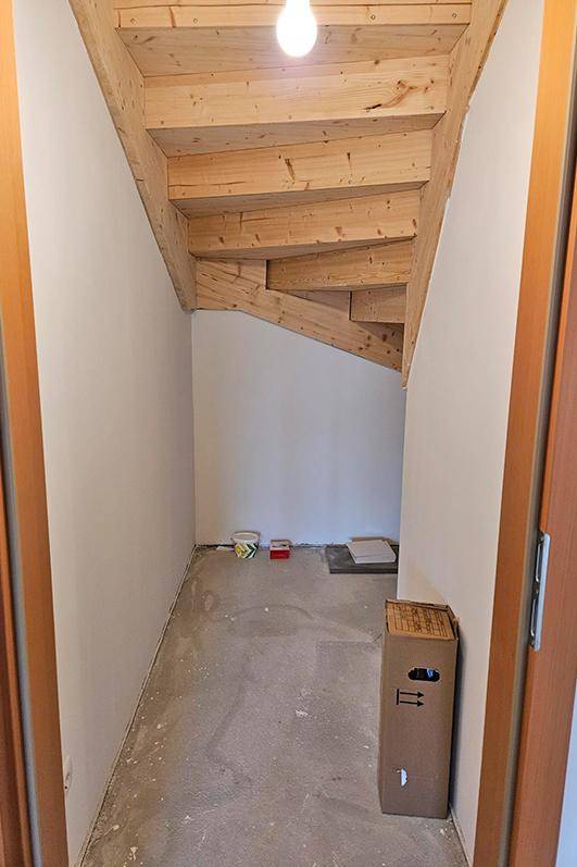 Praktischer Stauraum unter der Holztreppe mit sichtbaren Holzbalken.