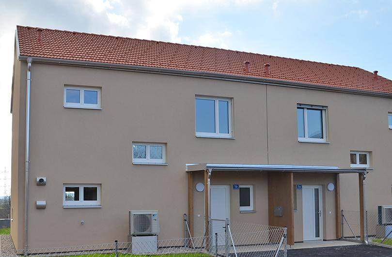 Die moderne Fassade des Reihenhauses mit großen Fenstern und einem überdachten Eingangsbereich.