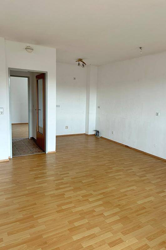 Heller Wohnbereich mit Laminatboden, bereit zur individuellen Gestaltung.