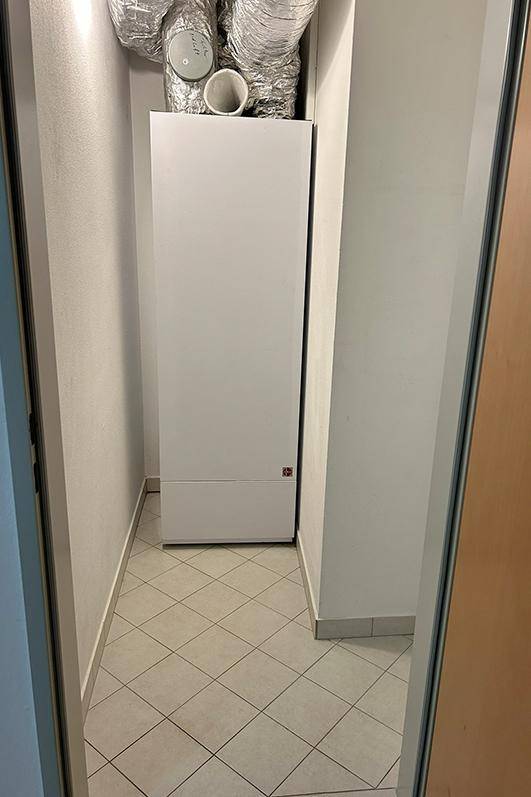 Kleiner Abstellraum mit Heizungsanlage und sichtbaren Lüftungsrohren.