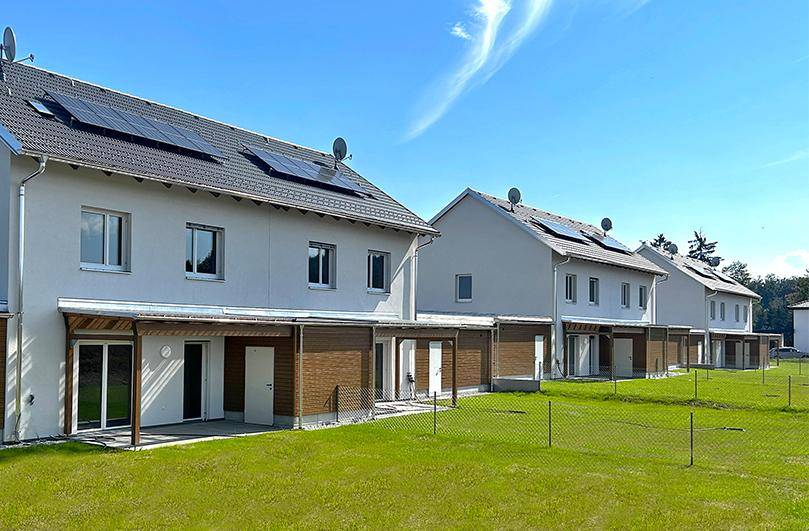 Reihe von modernen Einfamilienhäusern mit privaten Gärten und Solaranlagen auf den Dächern.
