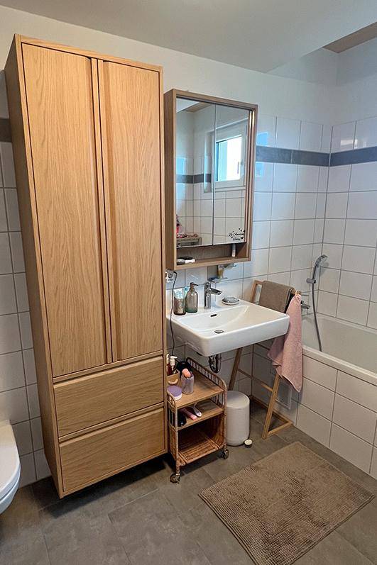 Helles Badezimmer mit Badewanne, Waschbecken und Holzschrank für zusätzlichen Stauraum.