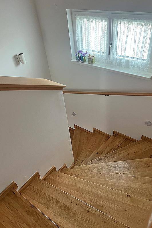 Helle Holztreppe mit Fenster, die zu den oberen Etagen führt und viel Tageslicht bietet.