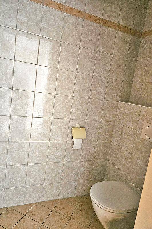 Separate Toilette mit Wand-WC und hellen Fliesen, einfach und funktional gestaltet.