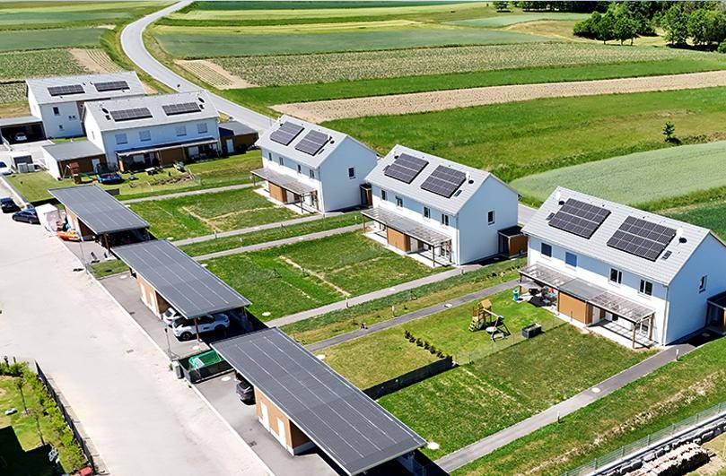 Übersicht einer Wohnsiedlung mit modernen Häusern, Solaranlagen, Carports und Spielplatz.