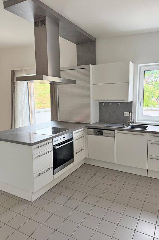 Helle Küche mit Kochinsel, integriertem Backofen und Spülmaschine, ideal für kulinarische Aktivitäten.