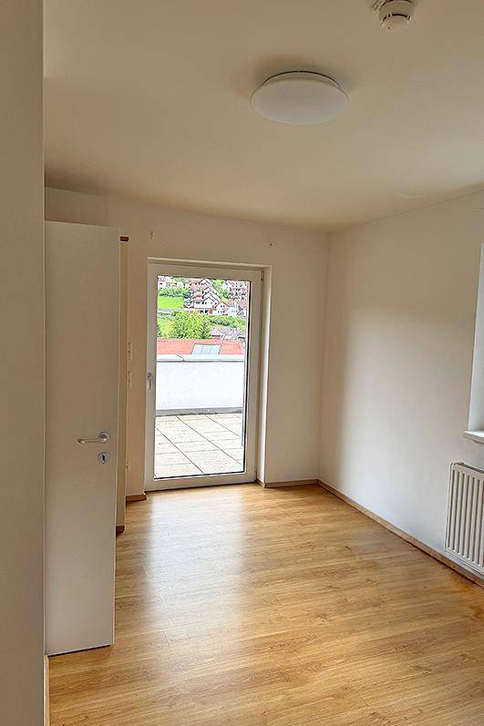 Helles Zimmer mit Laminatboden und direktem Zugang zu einer großzügigen Außenterrasse.