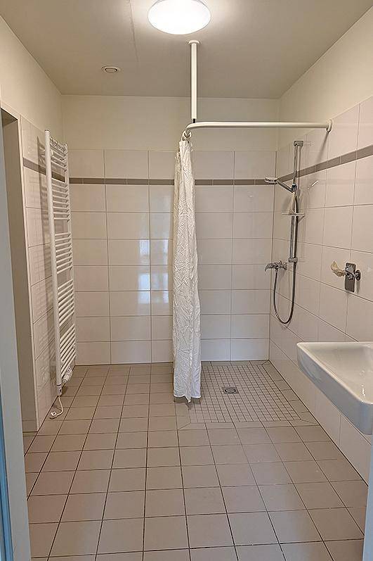 Geräumiges Badezimmer mit ebenerdiger Dusche, Waschbecken und beheiztem Handtuchhalter.