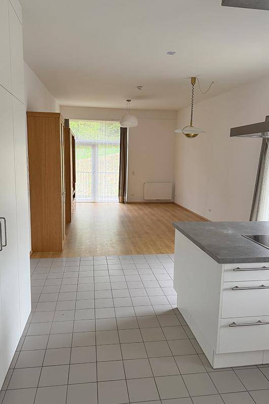 Offener Wohn-Essbereich mit moderner Küche, Kochinsel und Zugang zu einem Balkon.