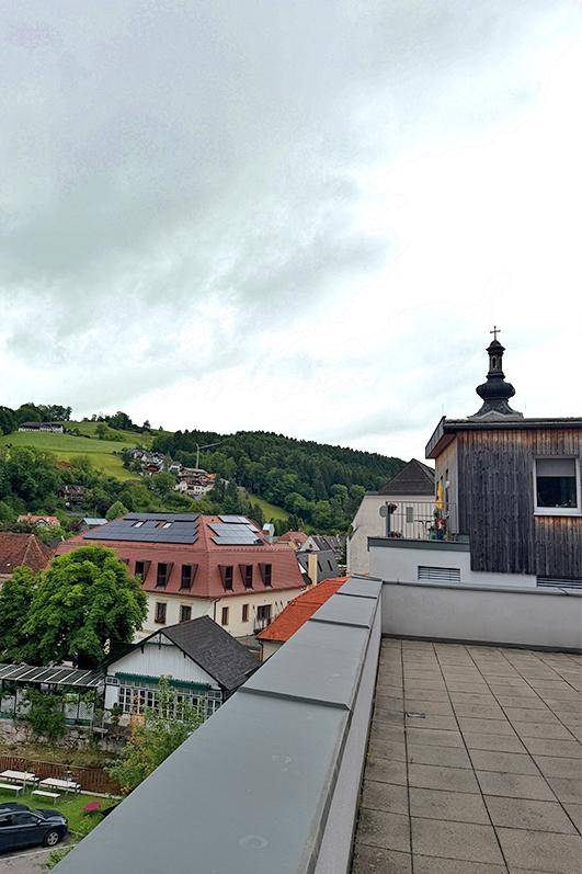 Weitläufige Terrasse mit Panoramablick über das Dorf und die umliegende grüne Landschaft.