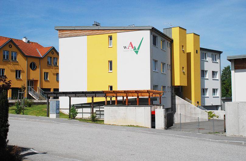 Ansicht des modernen Wohngebäudes mit Carport und farbiger Fassadengestaltung.