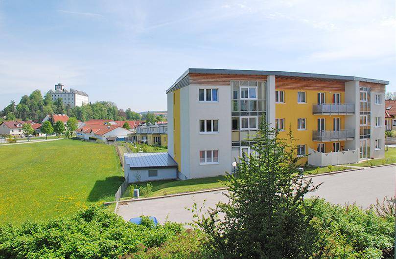 Wohngebäude mit moderner Architektur und weitem Blick auf eine Grünfläche und eine Burg.