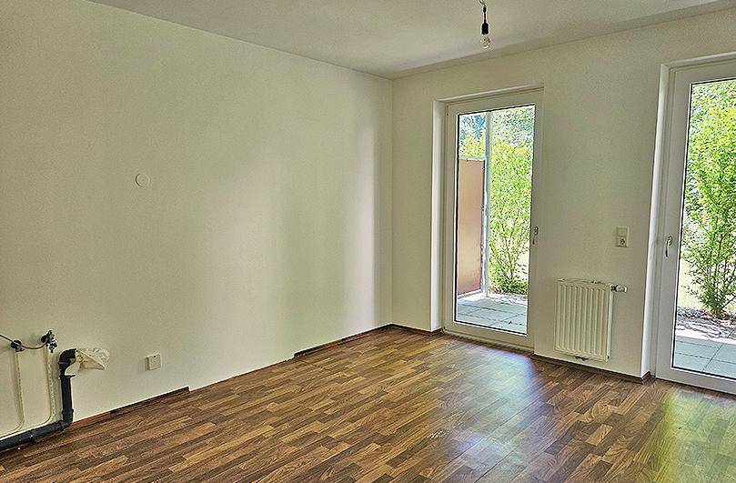Geräumiges Zimmer mit Laminatboden und direktem Zugang zu einem Außenbereich.