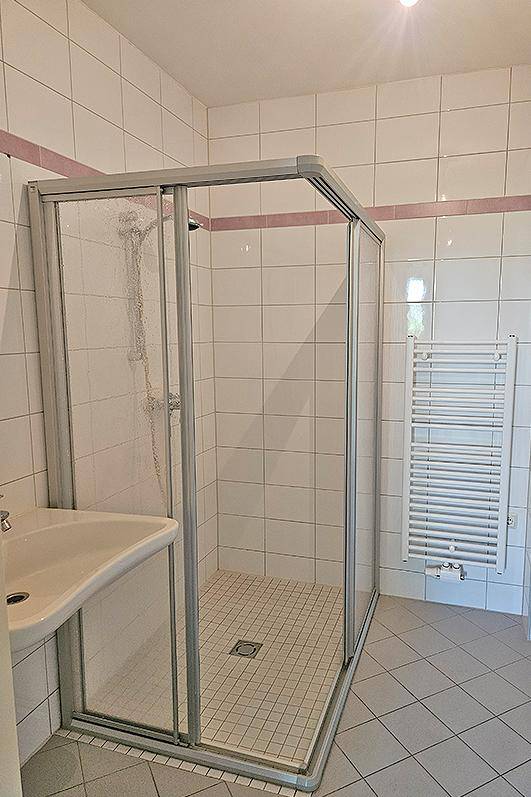 Badezimmer mit Duschkabine, Waschbecken und beheiztem Handtuchhalter.