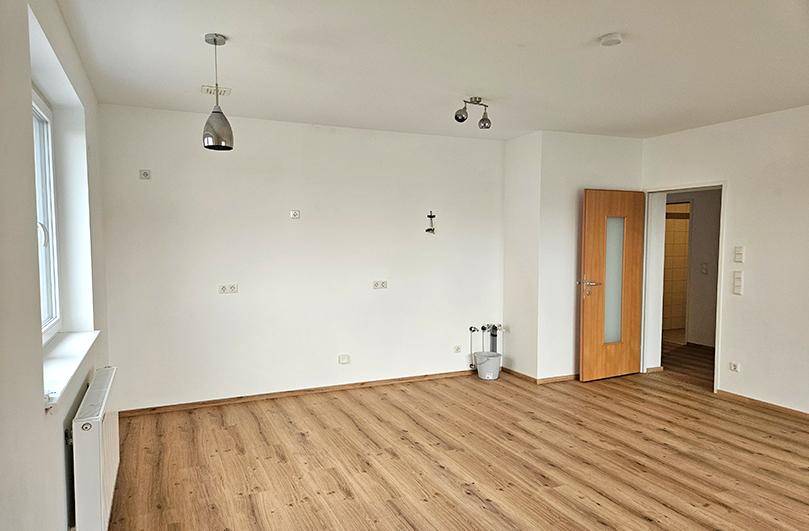 Geräumiger, heller Raum mit Laminatboden und Anschlüssen für eine mögliche Kücheninstallation.