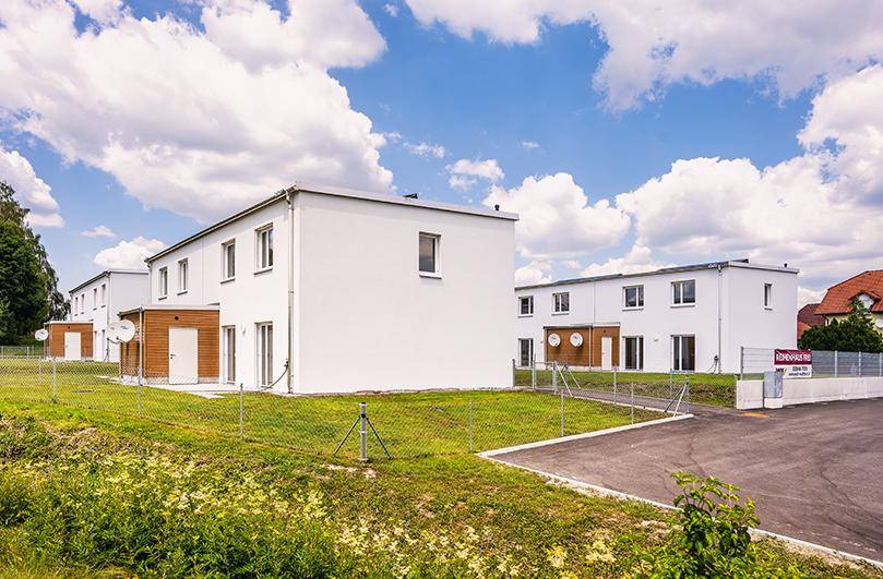 Reihenhäuser mit moderner Architektur, weißen Fassaden und kleinen Holzverkleidungen.