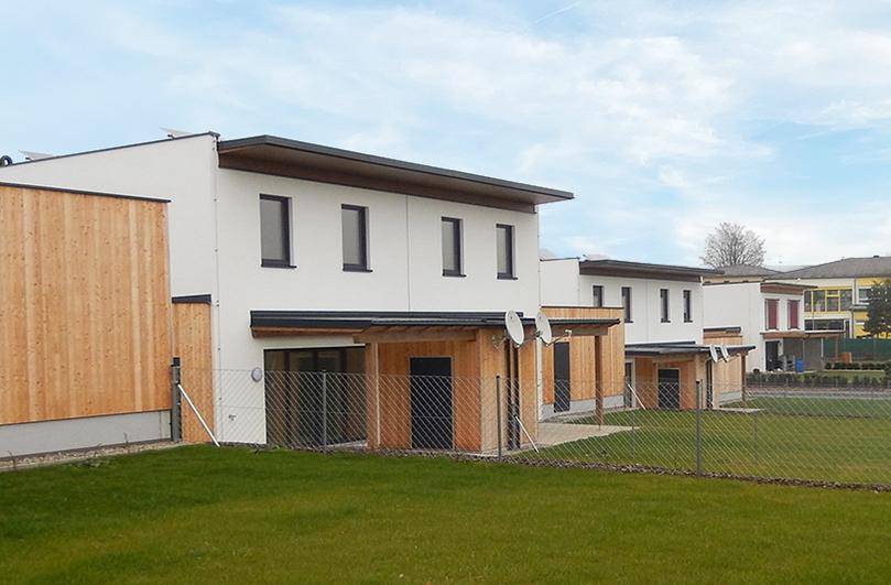 Reihenhausanlage mit moderner Architektur, Holzverkleidung und grünen Rasenflächen.