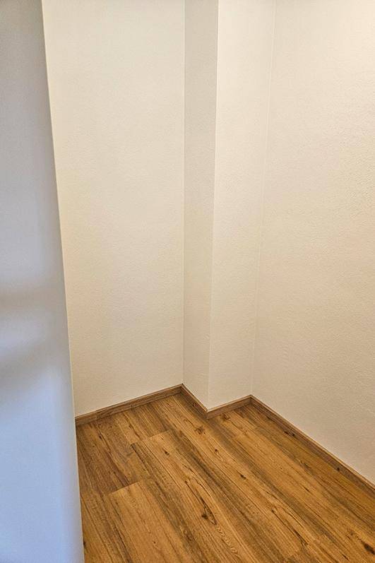 Kleiner, leerer Abstellraum mit Laminatboden und weißen Wänden, ideal für Lagerzwecke.