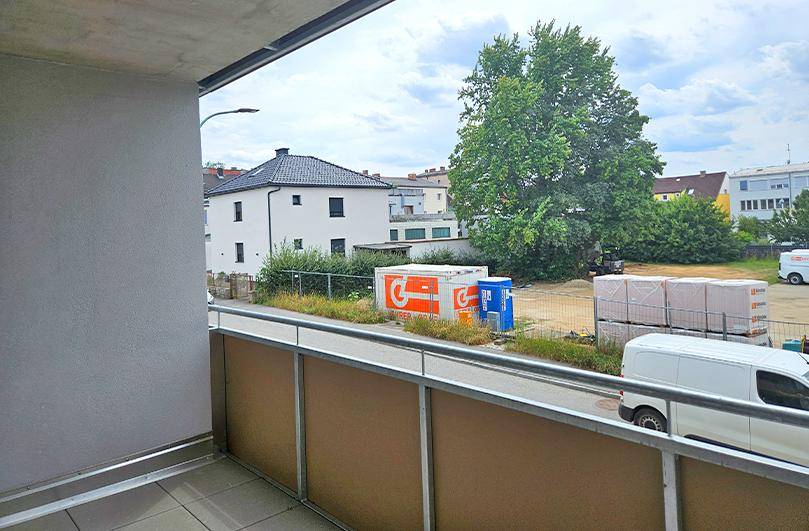 Balkon mit Ausblick auf die Umgebung, Bäume und weitere Gebäude in der Nachbarschaft.