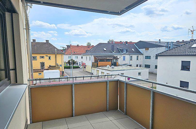 Balkon mit Fliesenboden und Blick auf die umliegenden Gebäude und die Straße.