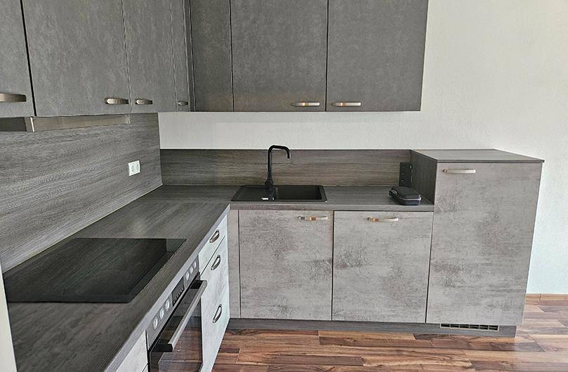 Moderne Küchenzeile in Grau mit integriertem Kochfeld, Spüle und Stauraum.