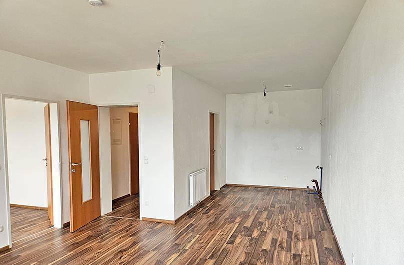 Geräumiger, leerer Wohnbereich mit Laminatboden und Heizkörper, bereit zur individuellen Gestaltung.