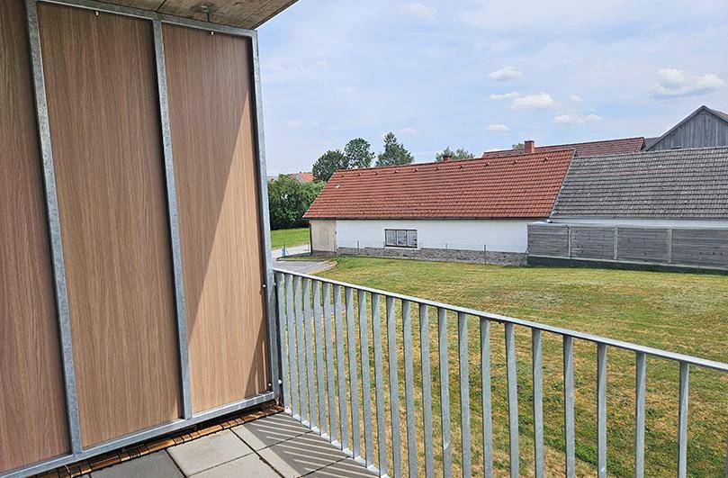 Balkon mit seitlichem Sichtschutz und weitem Blick über die ländliche Umgebung.