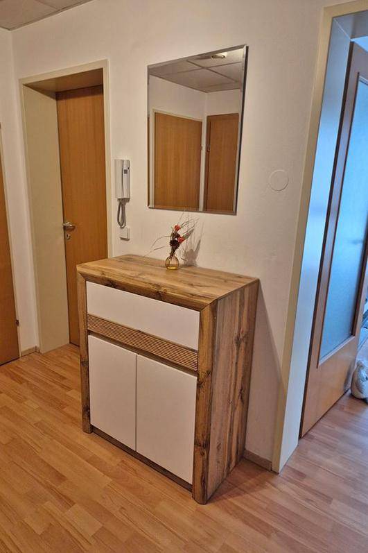 Heller Flur mit Holz-Kommode, Spiegel und Laminatboden.