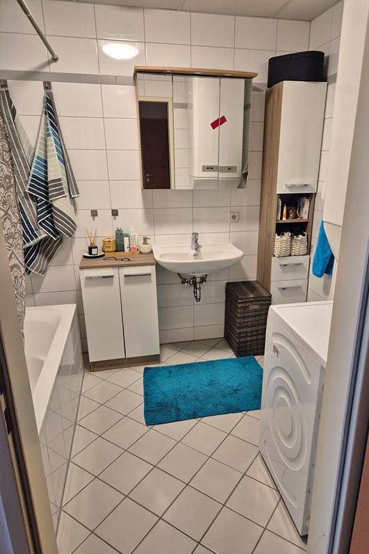 Helles Badezimmer mit Badewanne, Waschbecken und Waschmaschine.