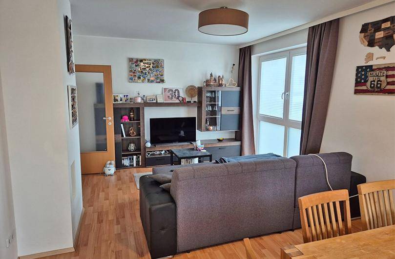 Wohnzimmer mit bequemer Couch, TV-Möbel und Laminatboden.