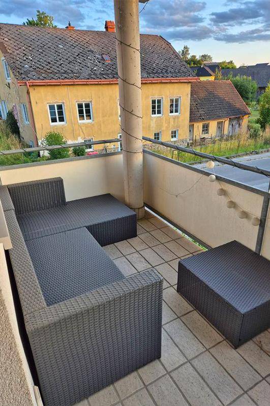 Gemütlicher Balkon mit Rattanmöbeln und Blick auf die Umgebung.