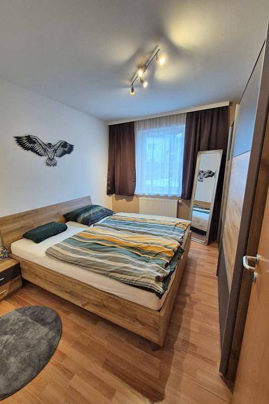 Schlafzimmer mit Doppelbett, Nachttischen und großem Fenster.