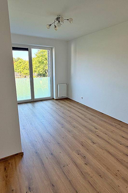 Helles Zimmer mit Laminatboden und großem Fenster, ideal als Schlaf- oder Arbeitszimmer.