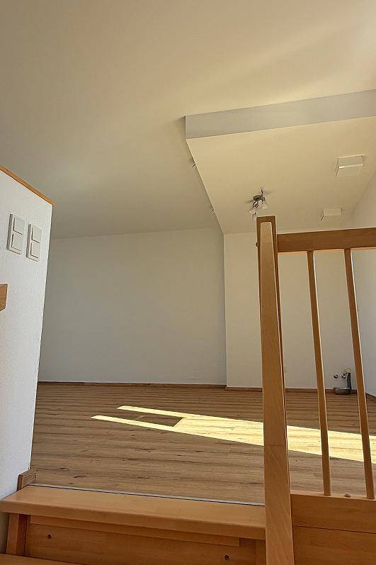 Heller Wohnbereich mit Laminatboden und Blick auf die Holztreppe.